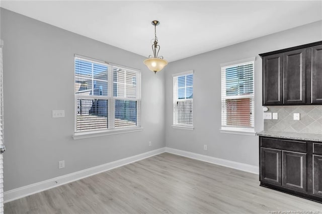 unfurnished dining area with light wood-style floors and baseboards