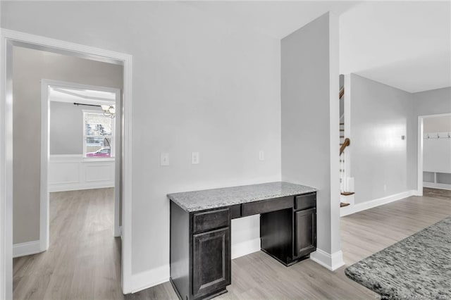 interior space featuring baseboards, light wood-style floors, and stairs