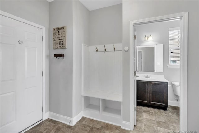 mudroom featuring baseboards and a sink