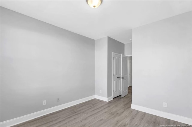 spare room featuring baseboards and wood finished floors