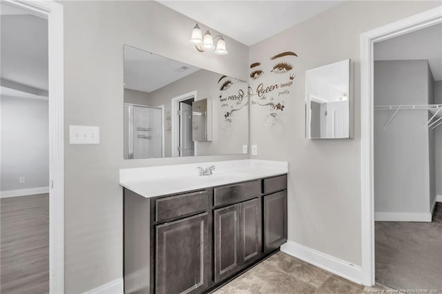 full bathroom with vanity, baseboards, and a shower with door