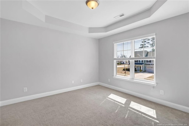 spare room with baseboards, a raised ceiling, visible vents, and carpet flooring