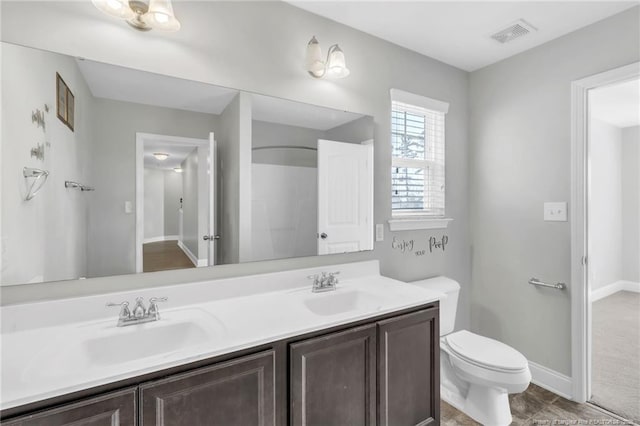 bathroom with a sink, visible vents, toilet, and double vanity