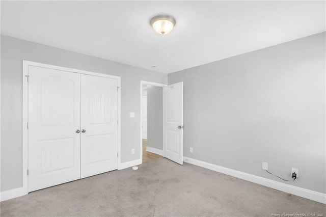 unfurnished bedroom featuring baseboards, carpet floors, and a closet