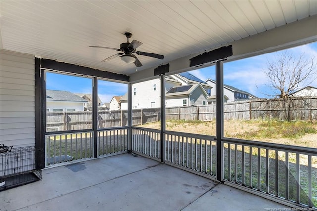 unfurnished sunroom with a residential view and ceiling fan