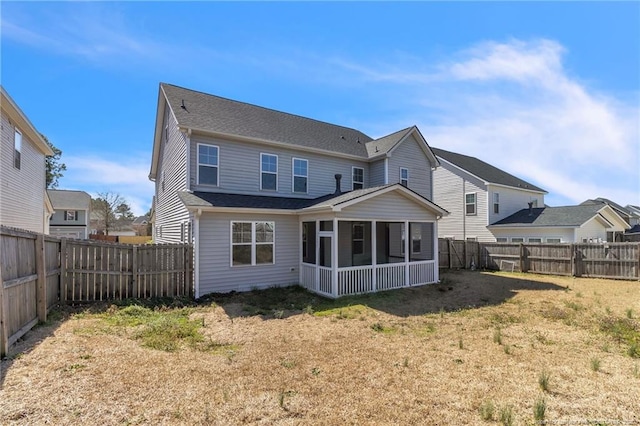 rear view of house with a yard, a fenced backyard, and a sunroom