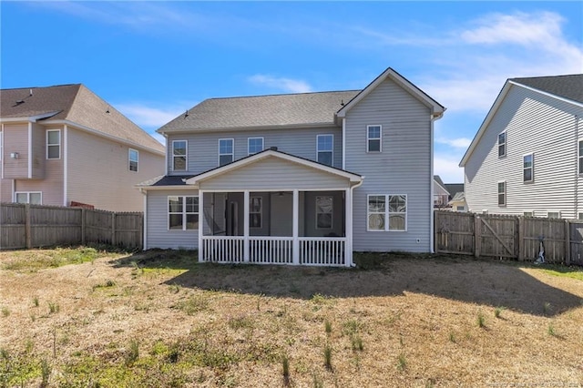 back of property featuring a lawn, a fenced backyard, and a sunroom