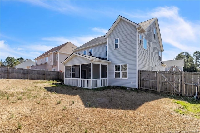 rear view of house with a gate, a yard, a fenced backyard, and a sunroom