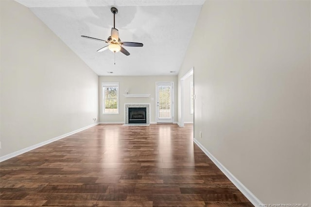 unfurnished living room with dark wood-type flooring, baseboards, ceiling fan, a fireplace with flush hearth, and lofted ceiling