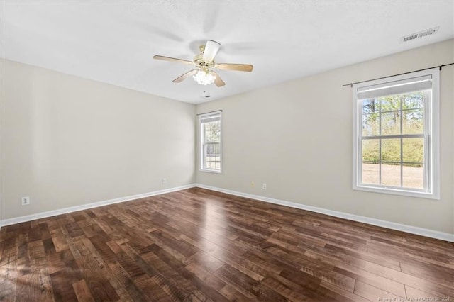 spare room with dark wood finished floors, baseboards, visible vents, and a ceiling fan