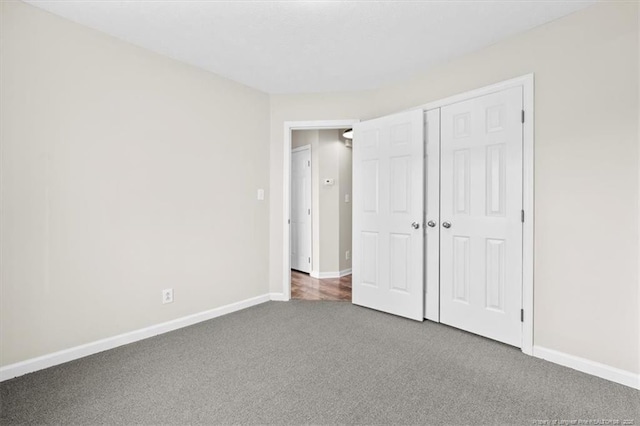 unfurnished bedroom featuring carpet, baseboards, and a closet