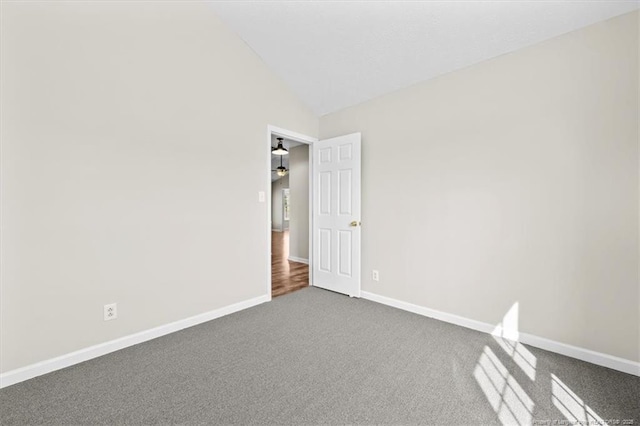 unfurnished room featuring baseboards, dark colored carpet, and high vaulted ceiling