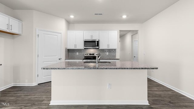 kitchen featuring dark stone countertops, white cabinetry, stainless steel appliances, and a sink