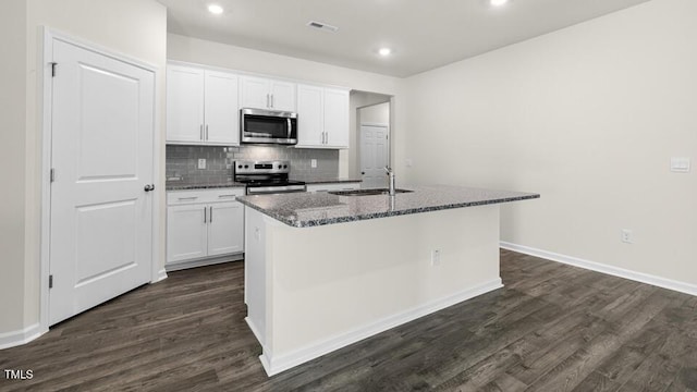 kitchen with visible vents, a sink, decorative backsplash, appliances with stainless steel finishes, and a kitchen island with sink