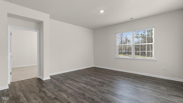 spare room with baseboards and dark wood-style floors