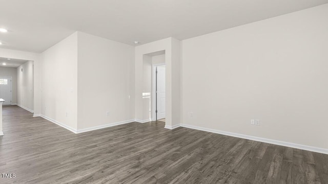 spare room with dark wood-type flooring, recessed lighting, and baseboards