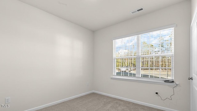 empty room with visible vents, light colored carpet, and baseboards