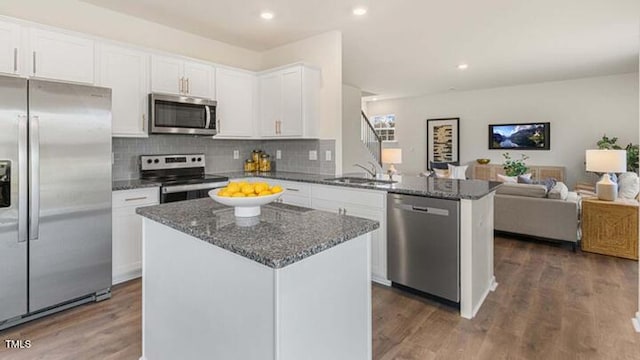 kitchen featuring dark wood-type flooring, open floor plan, white cabinets, stainless steel appliances, and a sink