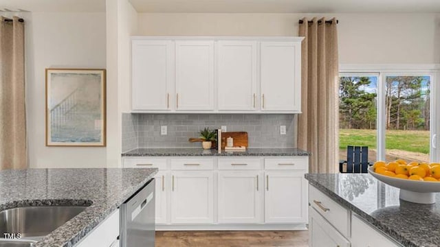 kitchen with decorative backsplash, white cabinetry, light wood-type flooring, and stainless steel dishwasher