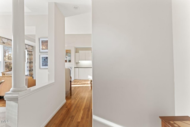 hallway featuring decorative columns and wood finished floors