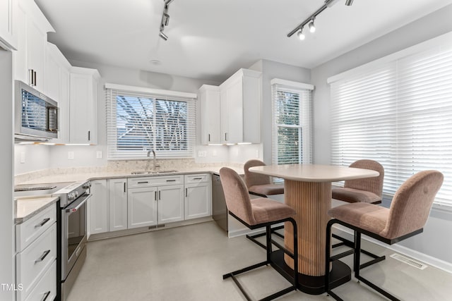 kitchen with visible vents, a sink, stainless steel appliances, white cabinets, and a kitchen bar