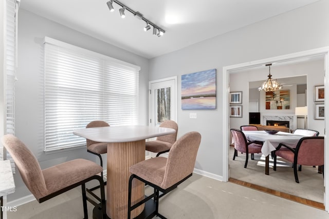 dining space with a wealth of natural light, baseboards, a high end fireplace, and a chandelier