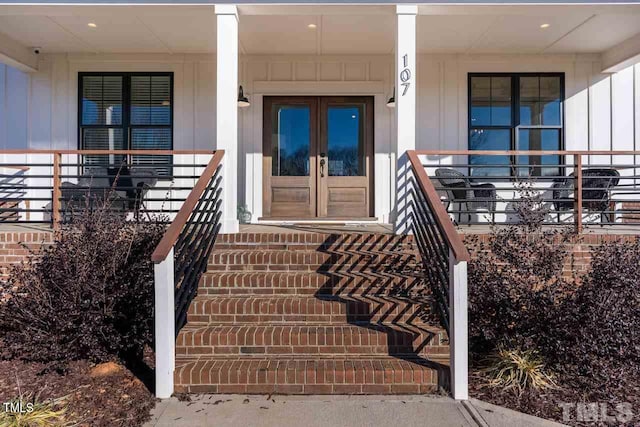 doorway to property with french doors, board and batten siding, and a porch