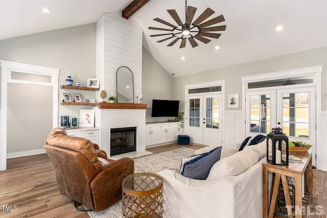 living area with a fireplace, recessed lighting, french doors, light wood-style floors, and beamed ceiling