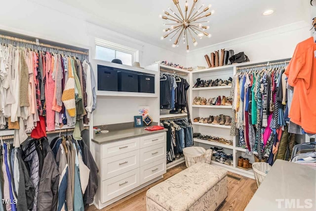 spacious closet with light wood-type flooring and a notable chandelier