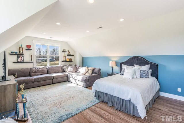 bedroom with wood finished floors, visible vents, baseboards, recessed lighting, and vaulted ceiling