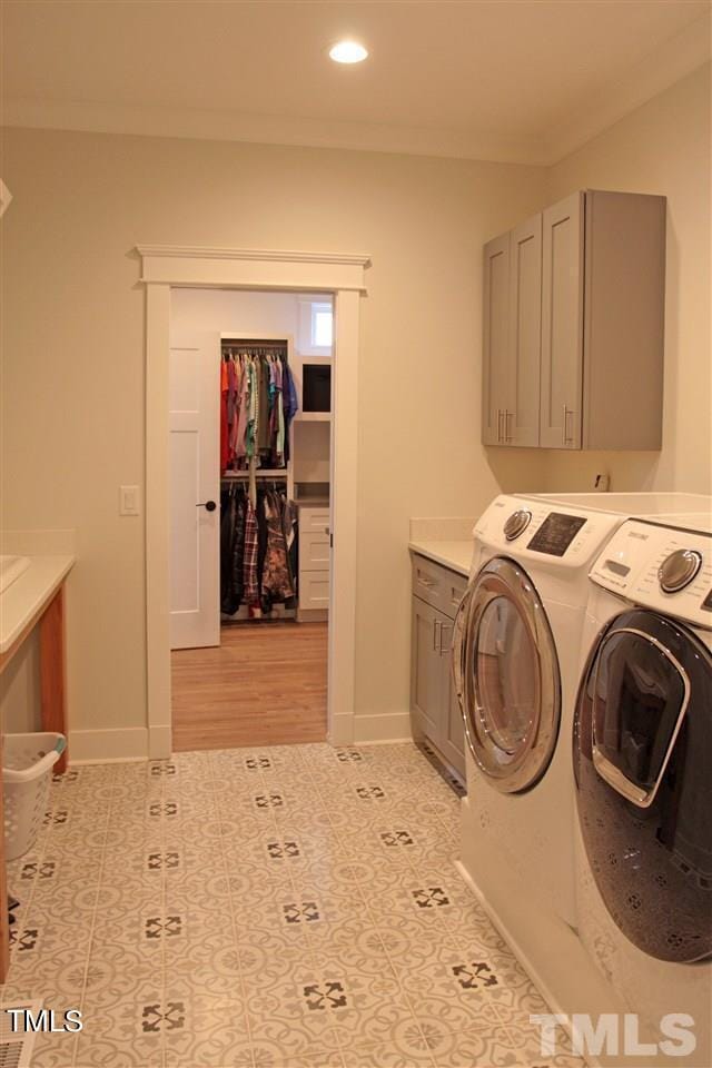 washroom featuring washing machine and clothes dryer, cabinet space, crown molding, and baseboards