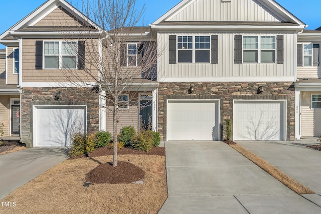 multi unit property with stone siding, board and batten siding, an attached garage, and driveway