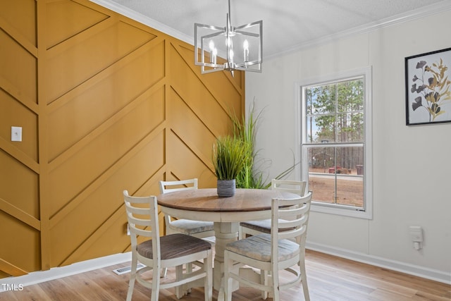 dining area featuring an inviting chandelier, crown molding, light wood-type flooring, and a wealth of natural light