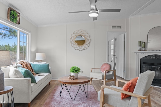 living area featuring visible vents, ornamental molding, and wood finished floors