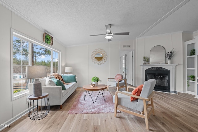 living area with visible vents, light wood-style flooring, and crown molding