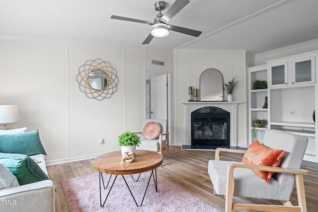 living area featuring visible vents, a textured ceiling, wood finished floors, and crown molding