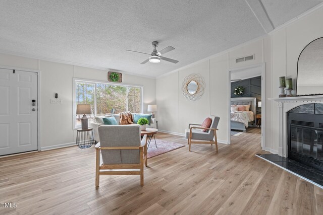 living area featuring wood finished floors, visible vents, and ornamental molding