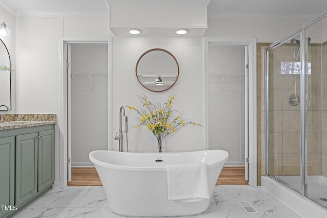 bathroom with a shower stall, a spacious closet, marble finish floor, and ornamental molding