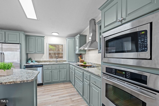 kitchen with a sink, wall chimney exhaust hood, gray cabinets, and stainless steel appliances