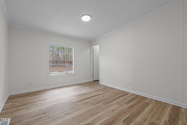 spare room with baseboards, light wood-style floors, ornamental molding, and a textured ceiling