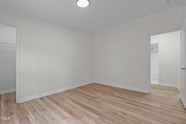 empty room featuring light wood-style flooring and ornamental molding