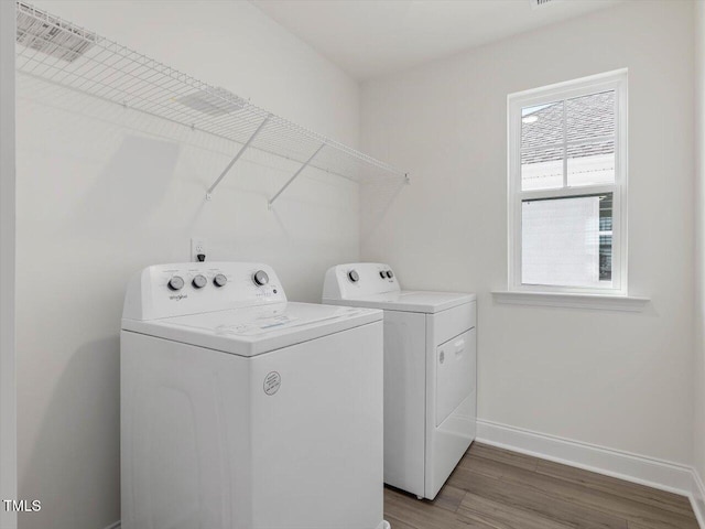 clothes washing area with washer and dryer, laundry area, wood finished floors, and baseboards