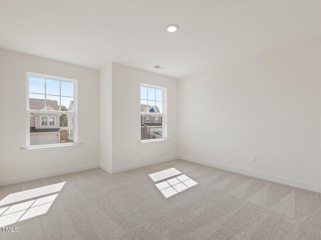 empty room featuring visible vents, baseboards, and light colored carpet