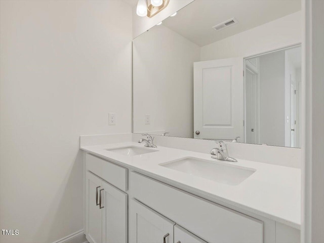 bathroom with double vanity, baseboards, visible vents, and a sink