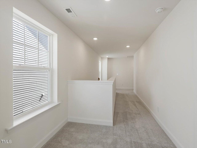 corridor featuring an upstairs landing, visible vents, light carpet, and baseboards