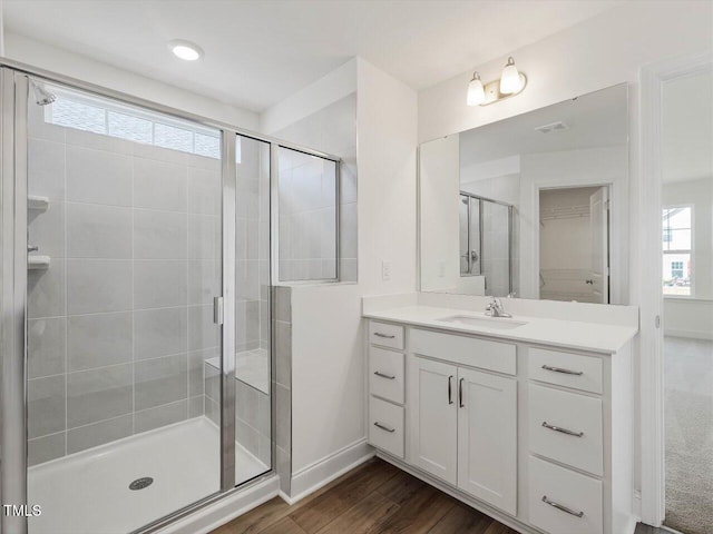 full bath with baseboards, wood finished floors, a stall shower, and vanity