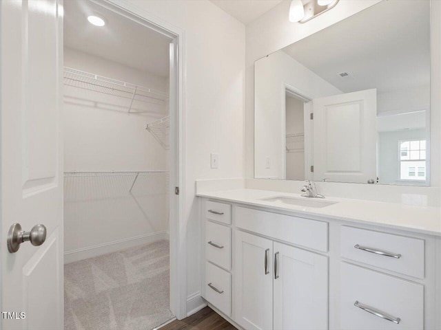 bathroom featuring vanity, a spacious closet, baseboards, and visible vents