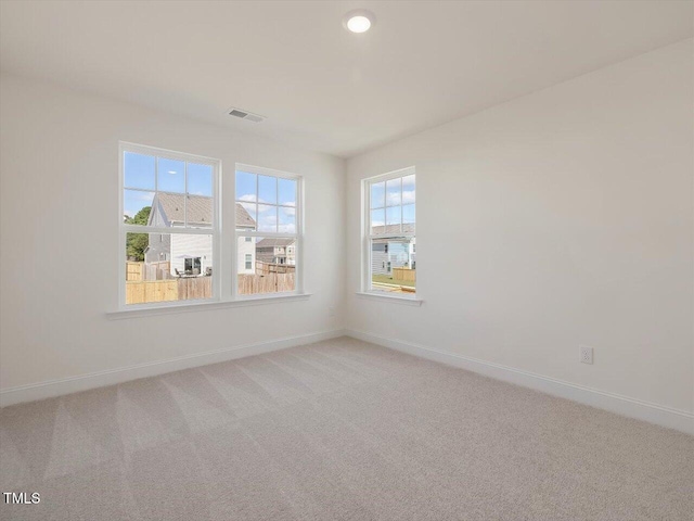 spare room with light carpet, visible vents, and baseboards