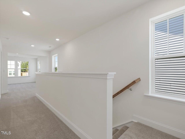 corridor with recessed lighting, an upstairs landing, light colored carpet, and baseboards