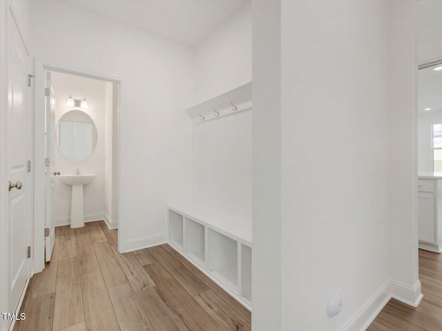 mudroom featuring light wood-type flooring, baseboards, and a sink